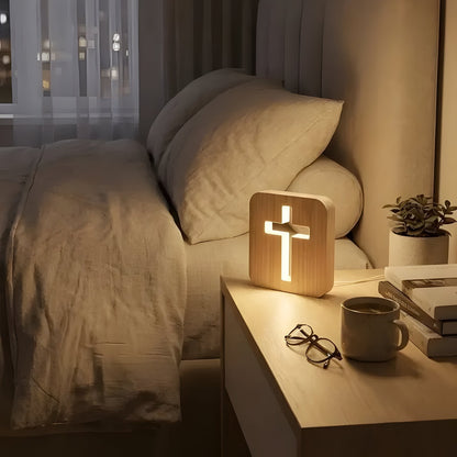 Wooden cross lamp on bedside table next to a soft pillow